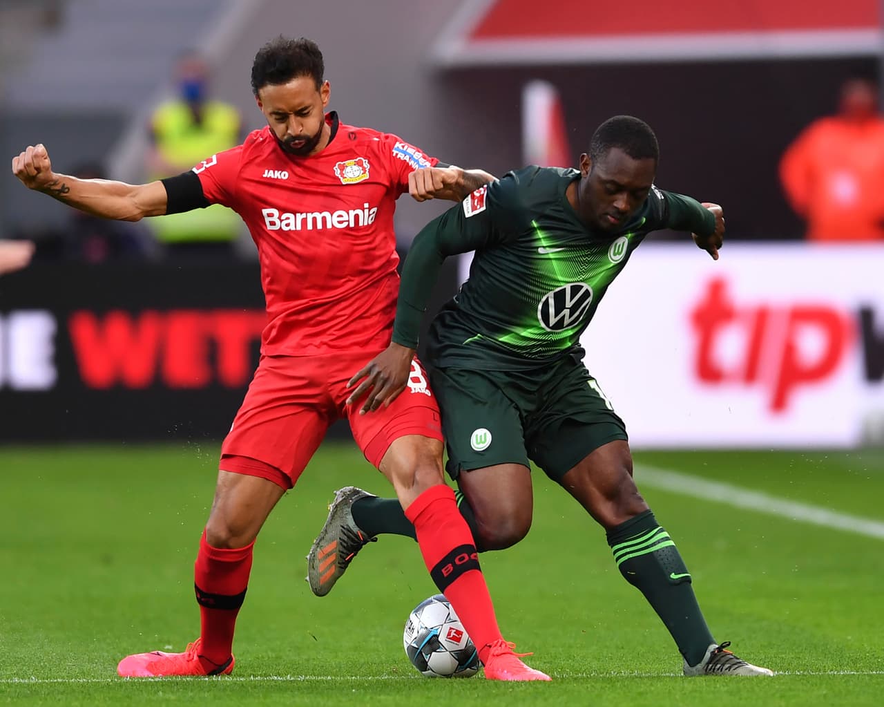 Karim Bellarabi dsiputa por la poseción del balón con el defensor del Wolfsburgo Jerome Roussillon.