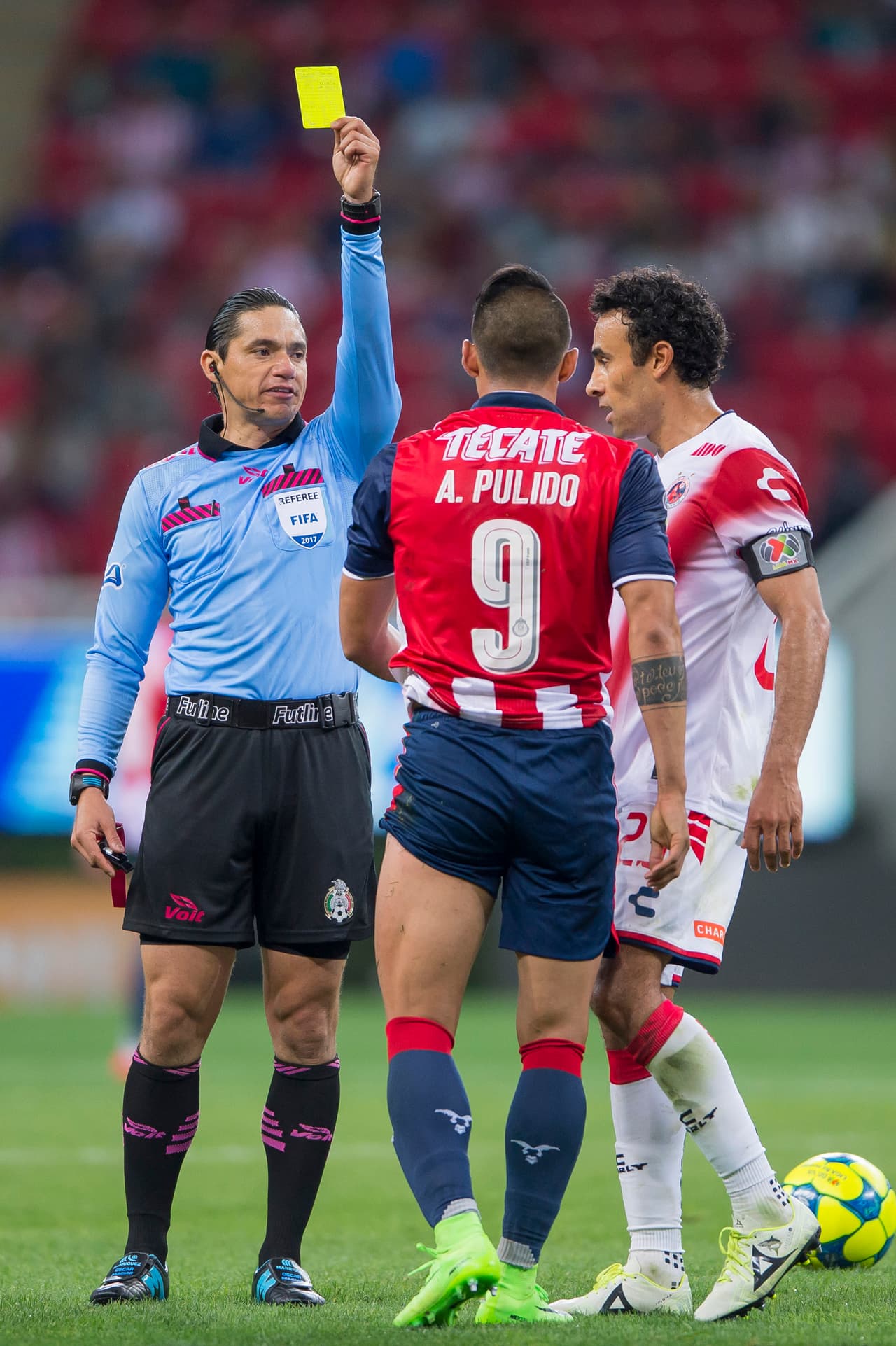 Alan Pulido recibe la tarjeta de amonestación tras cometer una falta innecesaria.