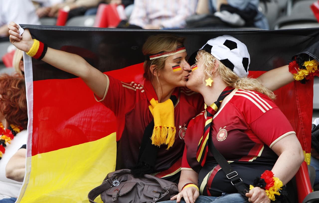 Two female supporters of Germany's team kiss as they hold their national flag before the opening match of the FIFA women's football World Cup Germany vs Canada at Berlin’s Olympic Stadium on June 26, 2011. AFP PHOTO / DAVID GANNON (Photo credit should read DAVID GANNON/AFP/Getty Images)