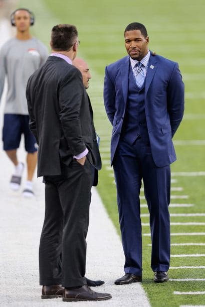Las leyendas Michael Strahan y Howie Long conversando en el campo.