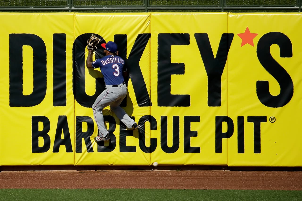 La acción comienza y el left fielder Delino DeShields de los Texas Rangers impide un cuadrangular ante los Kansas City Royals.
