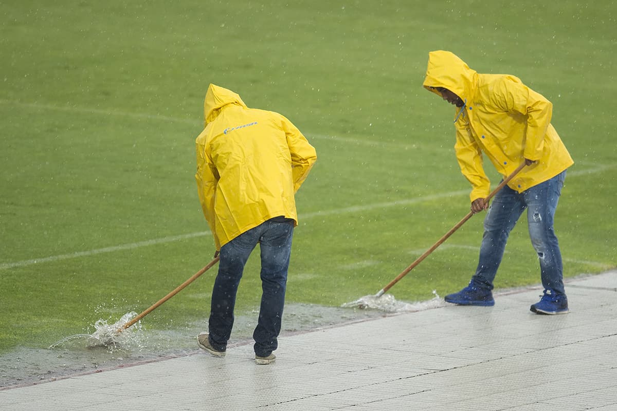 Asistentes de campo intentaron retirar el exceso de agua para el segundo tiempo del partido.