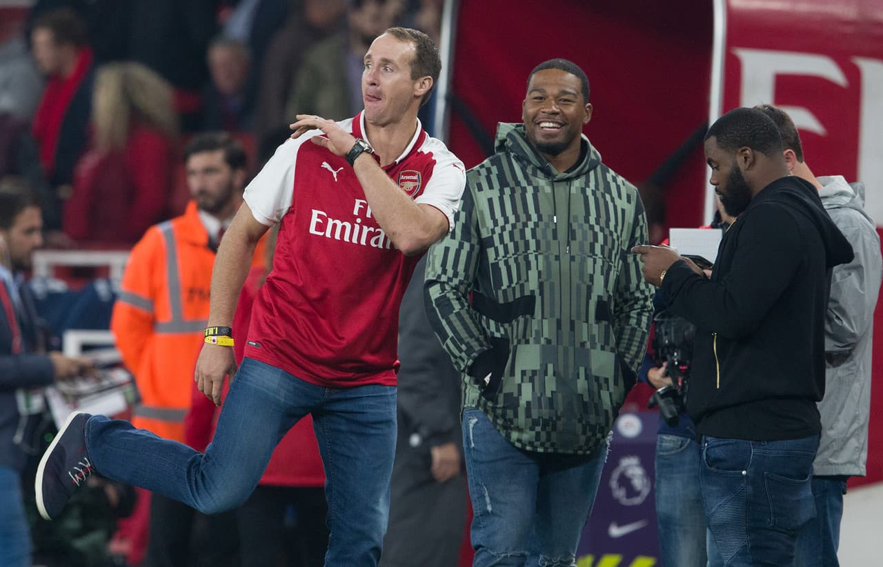 Drew Brees, ataviado con la playera del Arsenal, intentó dominar el balón de fútbol ante la mirada de Craig Robertson, linebacker de los New Orleans Saints.
<br>