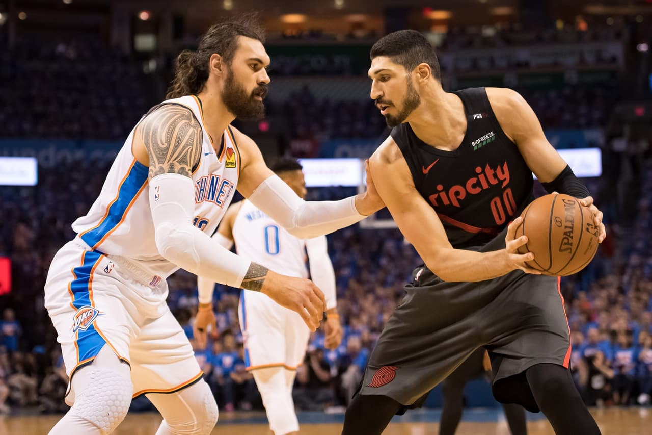 Enes Kanter (00) tratando de eludir la dura marca de Steven Adams.