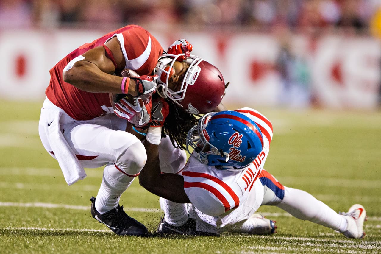 Jalen Julius de los Rebels de Mississippi detiene con fuerza a Keon Hatcher de los Razorbacks de Arkansas en el estadio de Razorback de Fayetteville, Arkansas. El esfuerzo sirvió para el triunfo 34-30 de los locales.