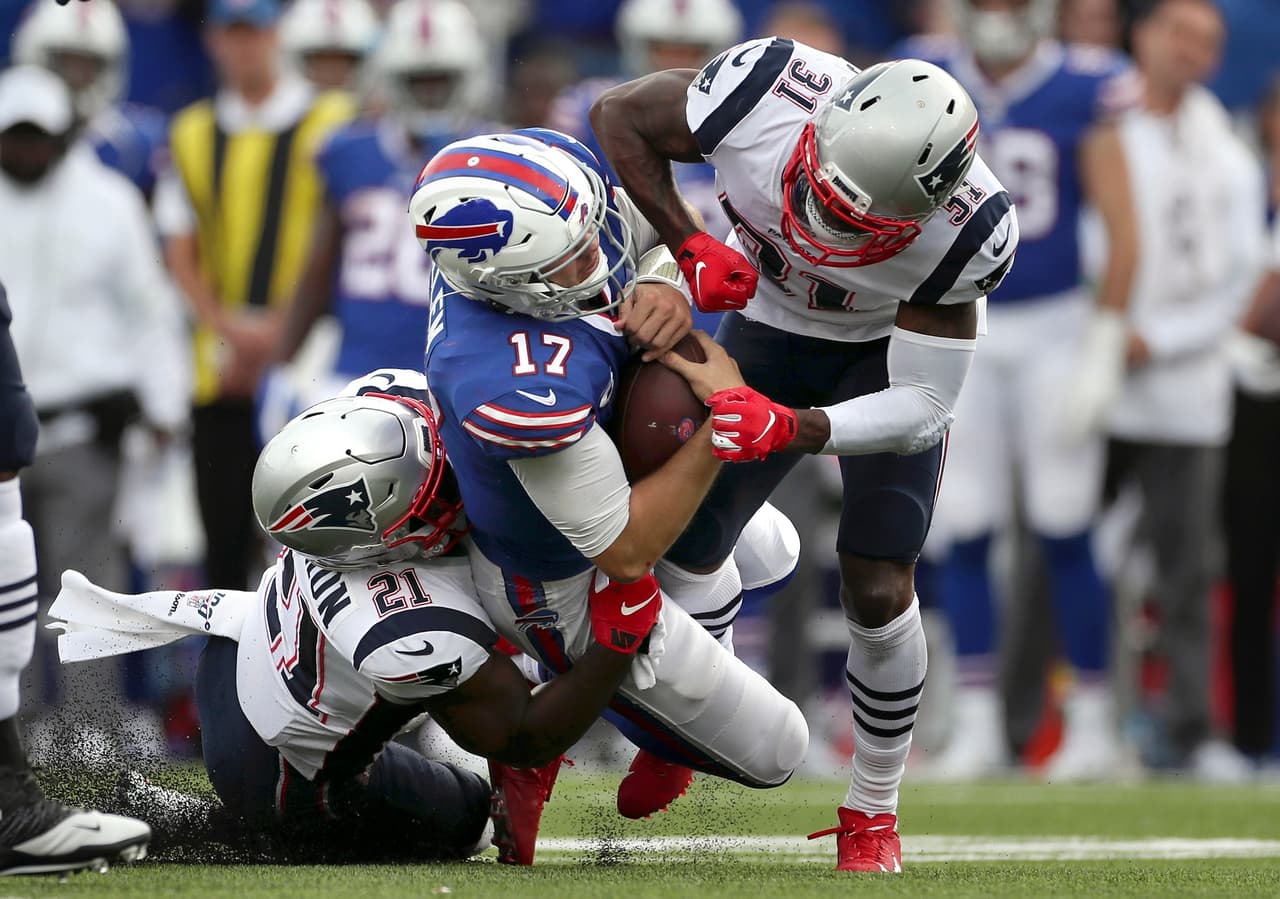 Josh Allen sale del campo de juego después de recibir un duro golpe por parte de la defensiva de los New England Patriots.