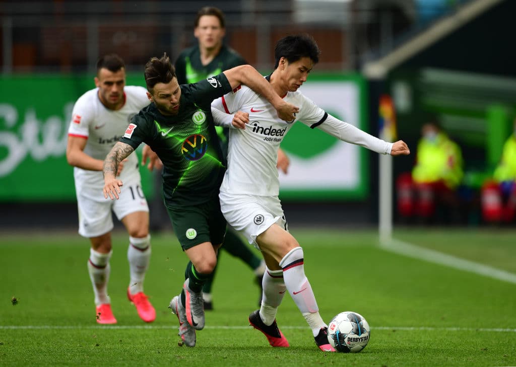 Daichi Kamada trata de salir con el balón controlado, pero el jugador del Wolfsburg Renato Steffen le presiona y manda el balón a saque de manos.