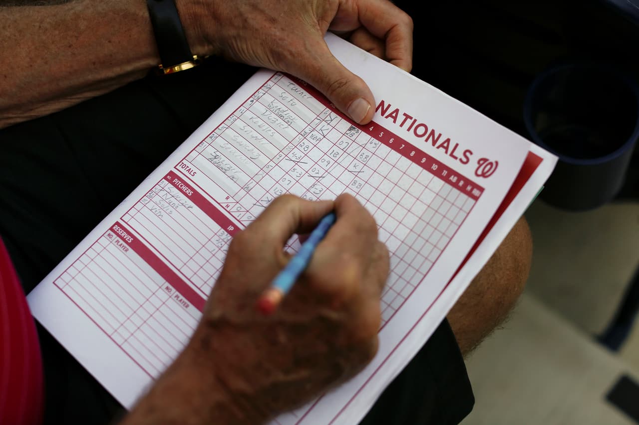 Por un lado, los fanáticos van a los encuentros a divertirse y a estar al tanto de cómo sus equipos van conformándose, como este aficionado que lleva la anotación del partido (boxscore) en el duelo emntre los Boston Red Sox y los Washington Nationals.
