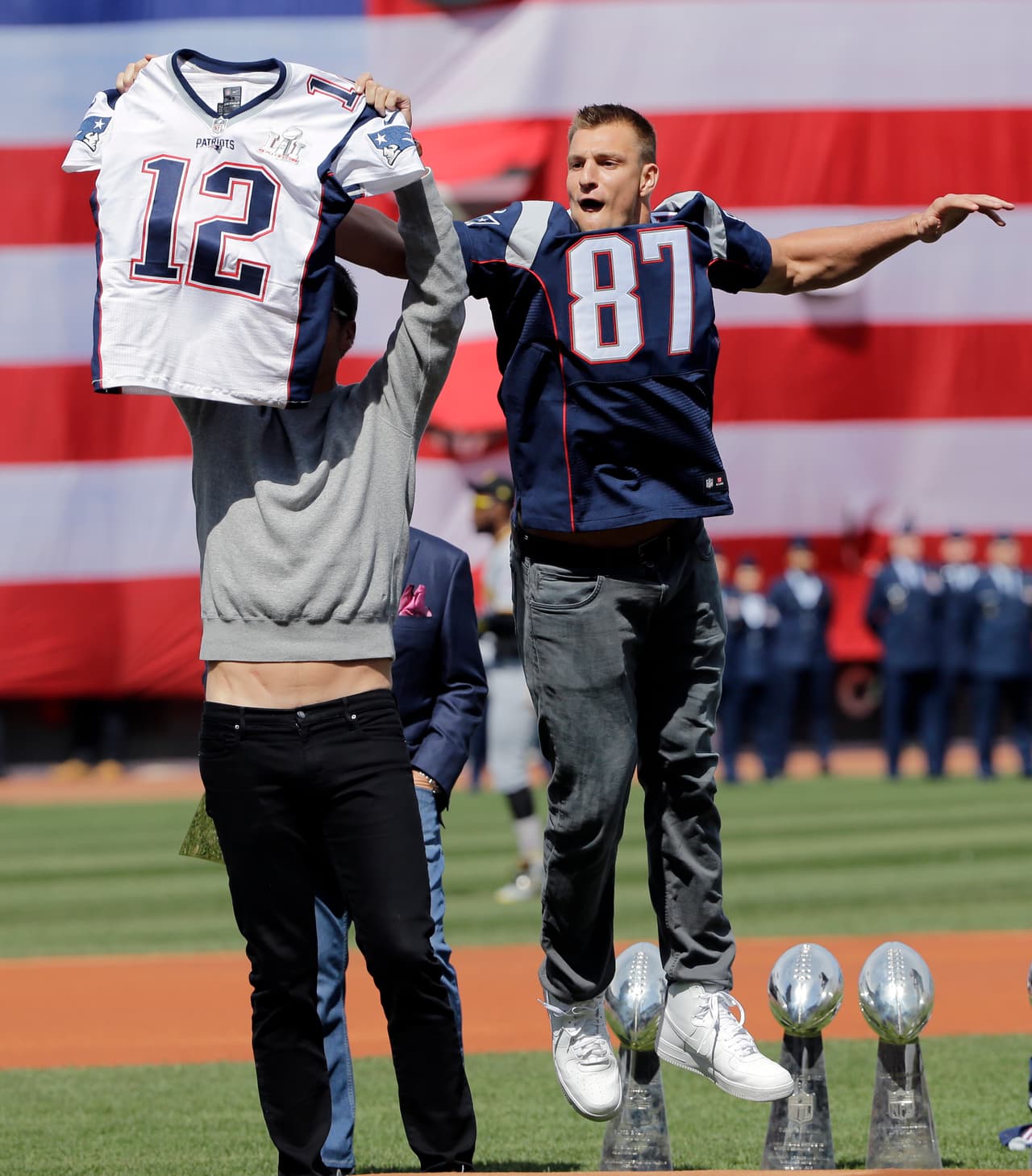 New England Patriots tight End Rob Gronkowski jumps to take quarterback Tom Brady's recovered Super Bowl jersey as he jokes around during baseball Boston Red Sox Home Opening Day ceremonies at Fenway Park, Monday, April 3, 2017, in Boston. The Red Sox face the Pittsburgh Pirates. (AP Photo/Elise Amendola).