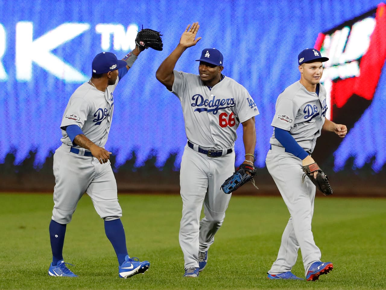 Los Angeles Dodgers Howie Kendrick, left, Yasiel Puig (66) and Joc Pederson celebrate after the Dodgers defeated the Washington Nationals 4-3 in Game 1 of a baseball National League Division Series at Nationals Park, Friday, Oct. 7, 2016, in Washington. (AP Photo/Pablo Martinez Monsivais)