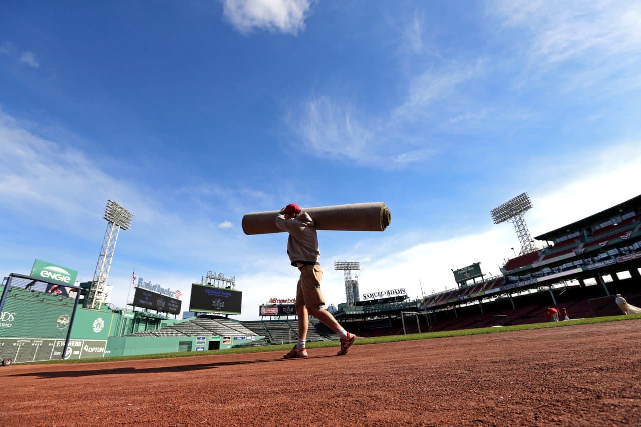 Un empleado de Fenway Park carga un tapete con el que se suele dejar la tierra del infield en perfectas, casi inmaculadas condiciones previo a un juego de pelota.