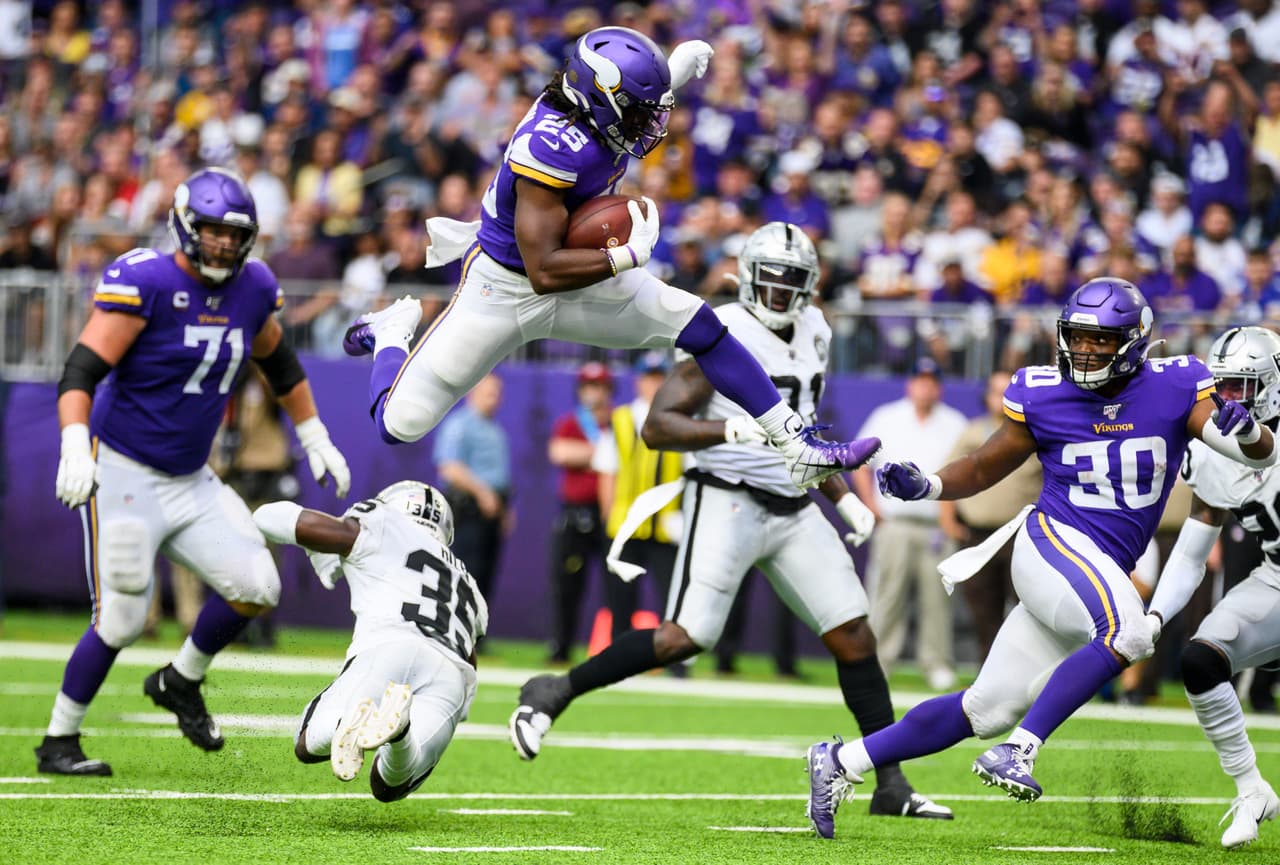 <b>Oakland Raiders 14-34 Minnesota Vikings.</b> Alexander Mattison brinca y evita la embestida de Curtis Riley, de los Raiders.