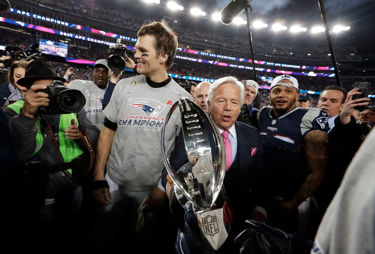 New England Patriots owner Robert Kraft, center, carries the trophy between quarterback Tom Brady, left, and safety Patrick Chung as they leave the field after the AFC championship NFL football game against the Jacksonville Jaguars, Sunday, Jan. 21, 2018, in Foxborough, Mass. The Patriots won 24-20. (AP Photo/David J. Phillip)