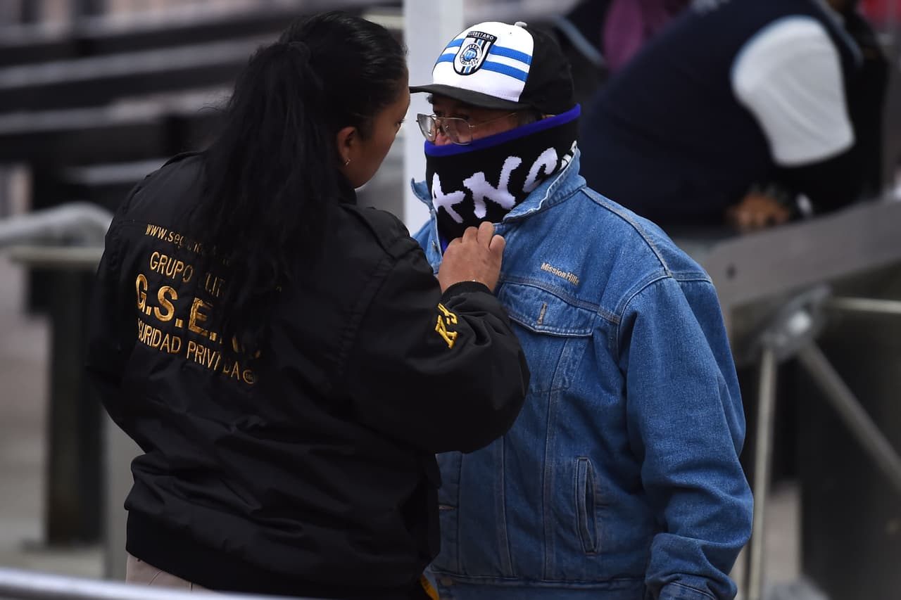 Mientras un aficionado es revisado a su ingreso al estadio, para evitar líos dentro, se aprecia la vestimenta, apta para una tarde-noche fría.