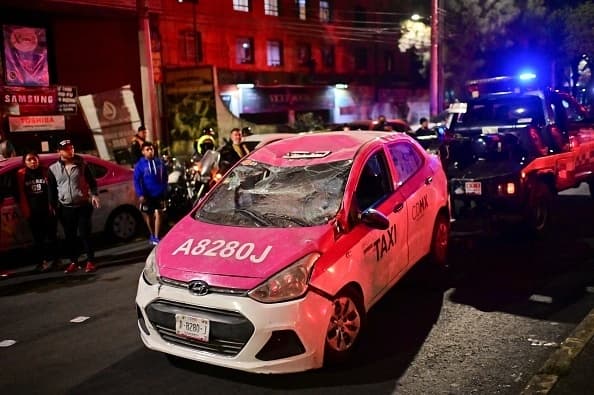 Los vagones cayeron sobre la calzada. En la imagen se puede ver cómo una grúa se lleva a
<b>un taxi dañado en el accidente. </b>
<br>