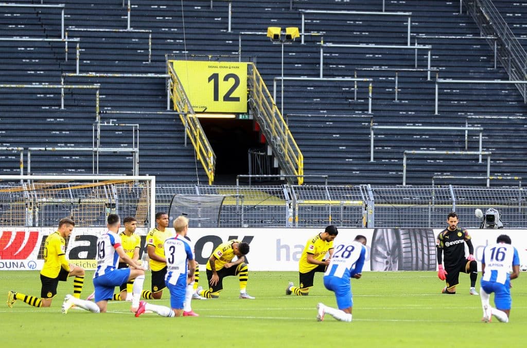 Jugadores del Borussia Dortmund y el Hertha Berlin se reúnen en el centro del campo con una rodilla en el césped para manifestarse por el asesinato de George Floyd a manos de un policía.