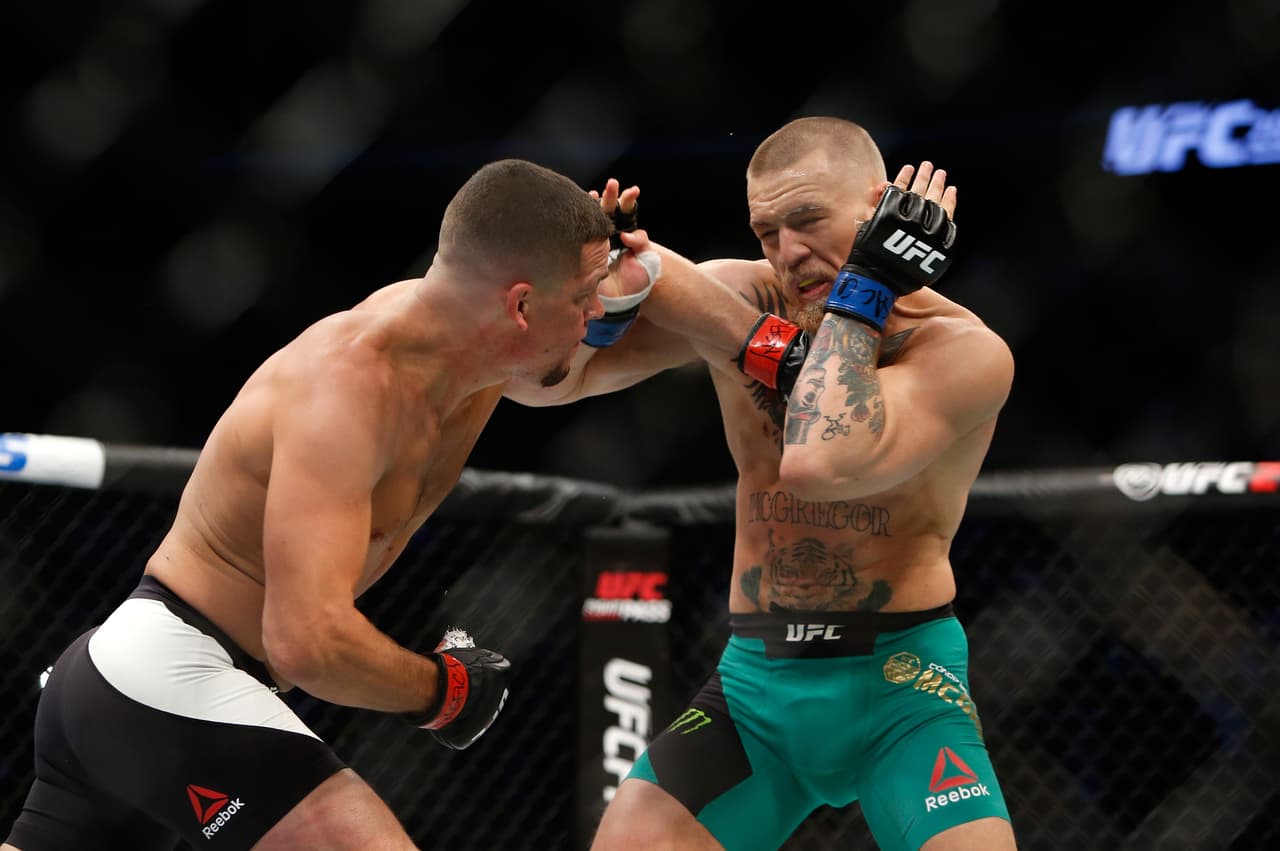McGregor (derecha) fue campeón de peso pluma y peso ligero, siendo el primero en UFC en ser campeón a la vez de ambos títulos.