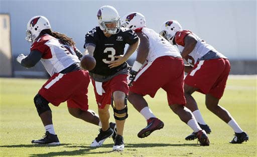 Palmer dejándole el ovoide al corredor Andre Ellington (AP-NFL).