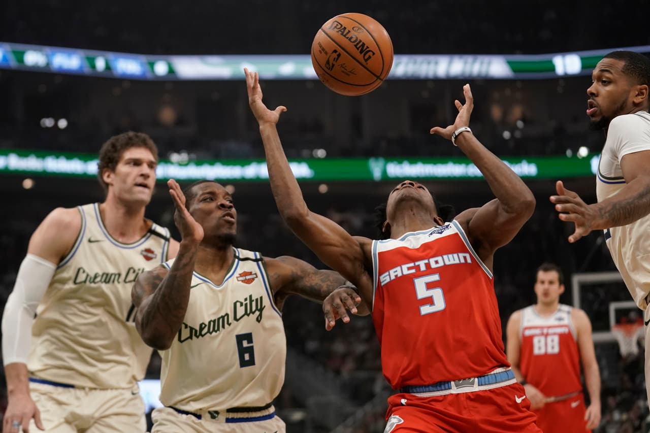 De Aaron Fox y Eric Bledsoe pelean por el balón en el aire ante la contemplación de propios y extraños.