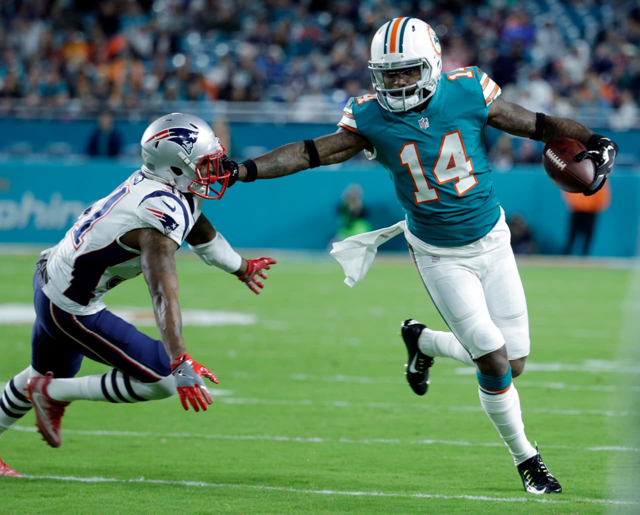 Miami Dolphins wide receiver Jarvis Landry (14) grabs the mask of New England Patriots cornerback Jonathan Jones (31), during the first half of an NFL football game, Monday, Dec. 11, 2017, in Miami Gardens, Fla. (AP Photo/Lynne Sladky)