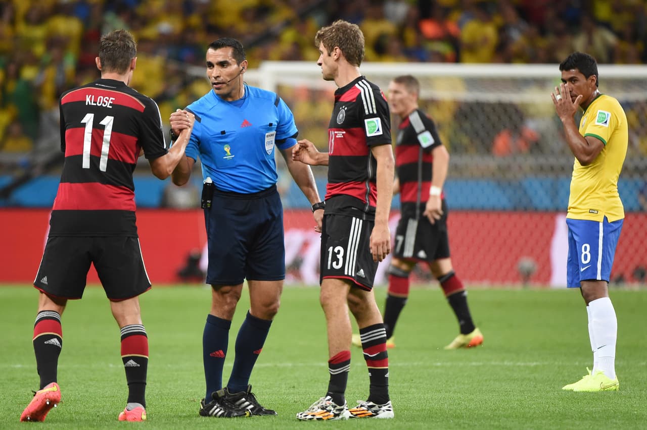 Germany's forward Miroslav Klose (L) and Germany's forward Thomas Mueller (C) go to shake hands with Mexican referee Marco Rodriguez (blue) as Brazil's midfielder Paulinho (R) reacts after the semi-final football match between Brazil and Germany at The Mineirao Stadium in Belo Horizonte during the 2014 FIFA World Cup on July 8, 2014. AFP PHOTO / PATRIK STOLLARZ (Photo credit should read PATRIK STOLLARZ/AFP via Getty Images)