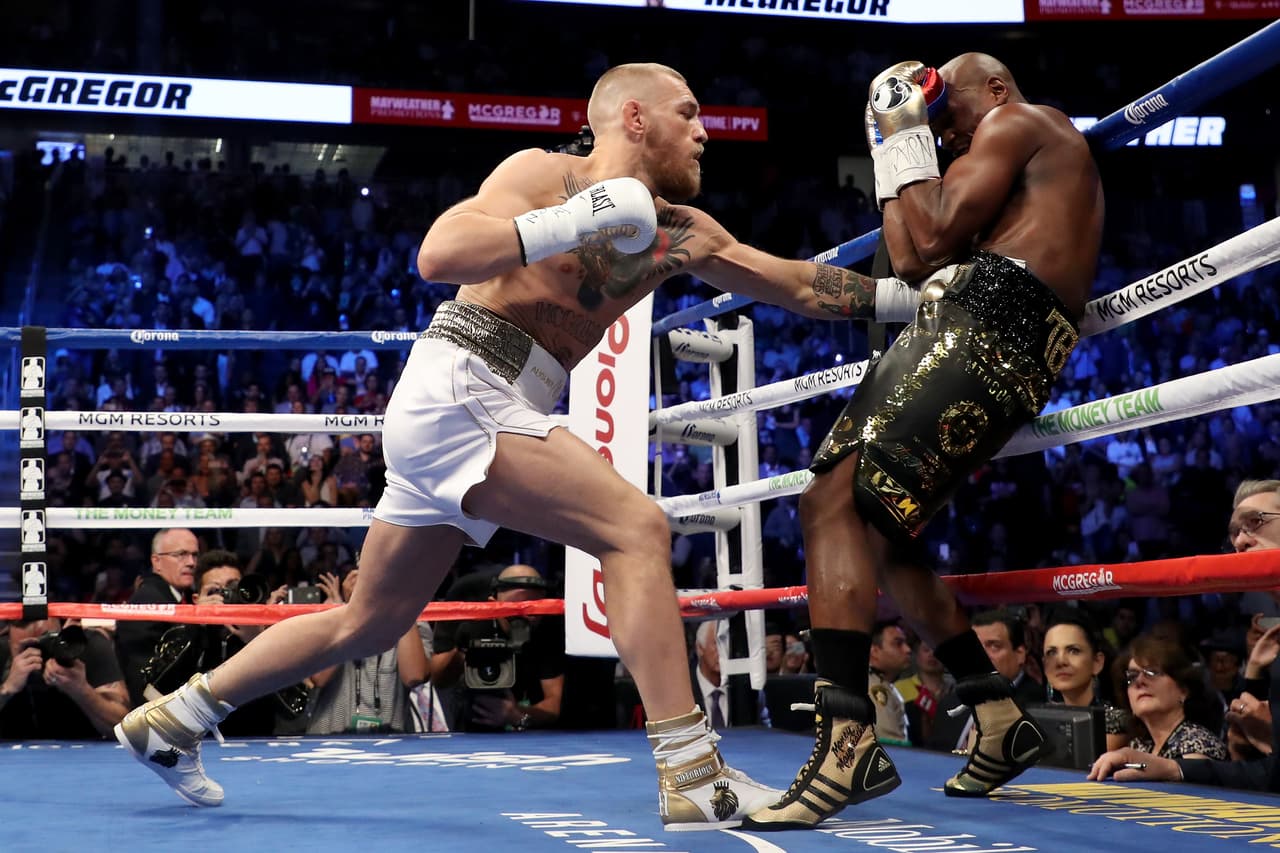 LAS VEGAS, NV - AUGUST 26: (L-R) Conor McGregor throws a punch at Floyd Mayweather Jr. during their super welterweight boxing match on August 26, 2017 at T-Mobile Arena in Las Vegas, Nevada. (Photo by Christian Petersen/Getty Images)
