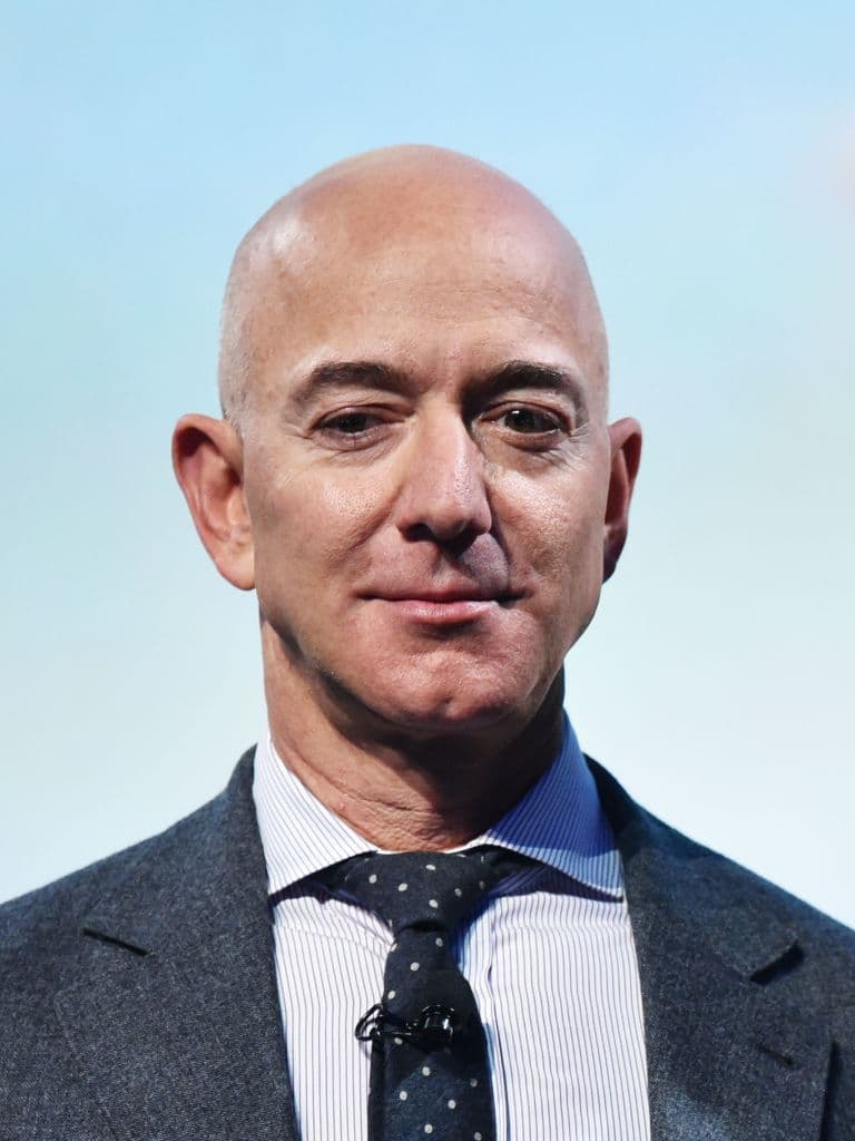 Bezos se encuentra parado sobre un letrero que dice: "¡Peligro! Un acantilado empinado. Caída fatal".