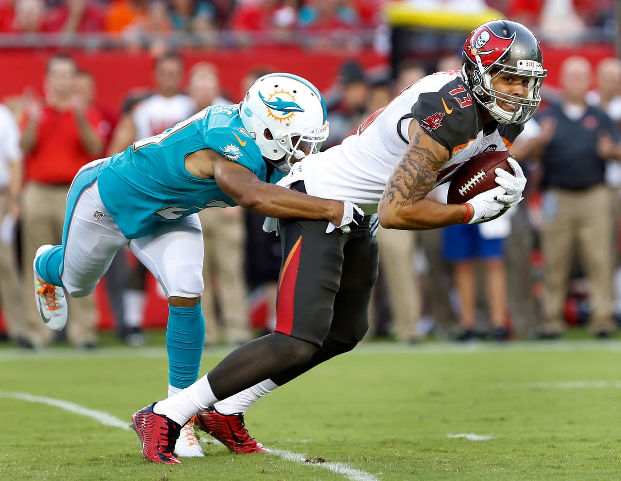 Tampa Bay Buccaneers wide receiver Mike Evans (13) is stopped by Miami Dolphins cornerback Brent Grimes (21) after a reception during the first quarter of an NFL preseason football game Saturday, Aug. 16, 2014, in Tampa, Fla. (AP Photo/Brian Blanco)
