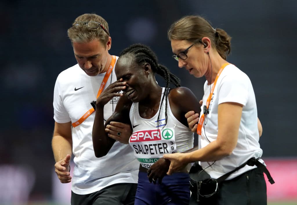 La atleta Lonah Chemtai Salpeter de 29 años es ayudada por los oficiales de la carrera luego de romper en llanto al cruzar la meta en la competencia.