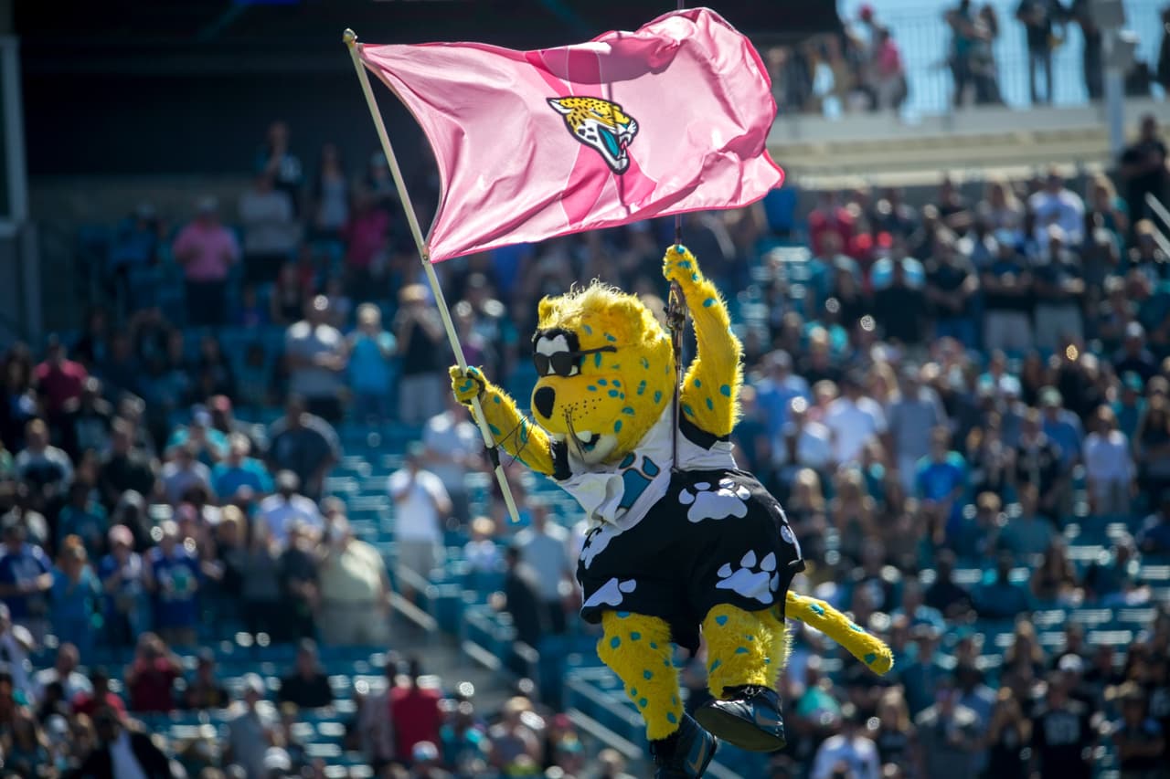 La mascota de los Jacksonville Jaguars, Jaxson Deville, portando una bandera del equipo en rosa, con motivo del apoyo a la detección temprana del cáncer de mama.