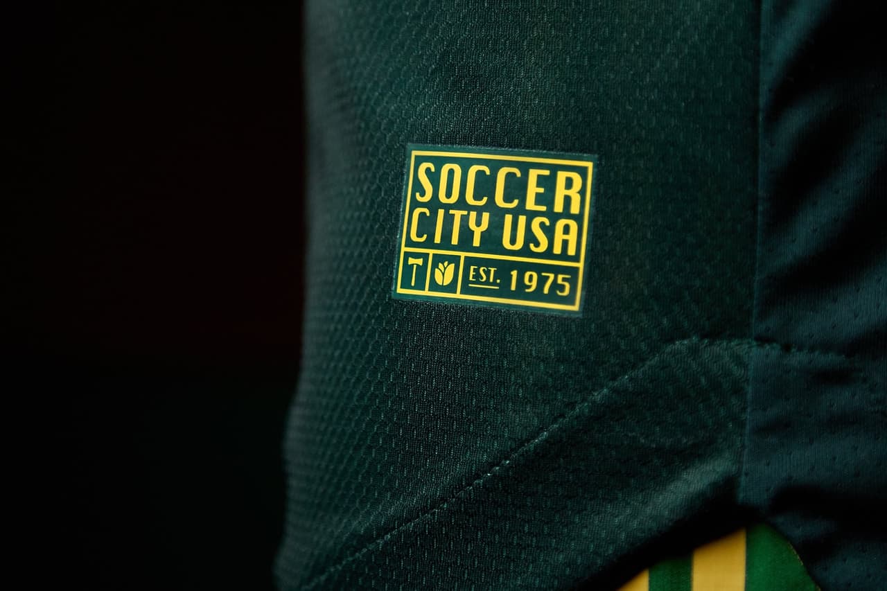La camisa cuenta con una etiqueta que reza “Soccer City USA” en la parte inferior izquierda.