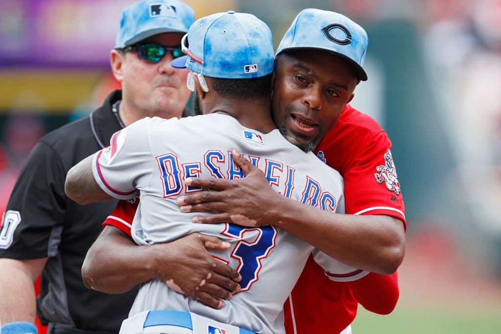 En pleno festejo del Día del Padre, el coach de primera base de los Cincinnati Reds, Delino DeShields, se funde en un abrazo con su hijo Delino DeShields Jr. center fielder de los Texas Rangers previo al inicio del juego en Great American Ball Park.
