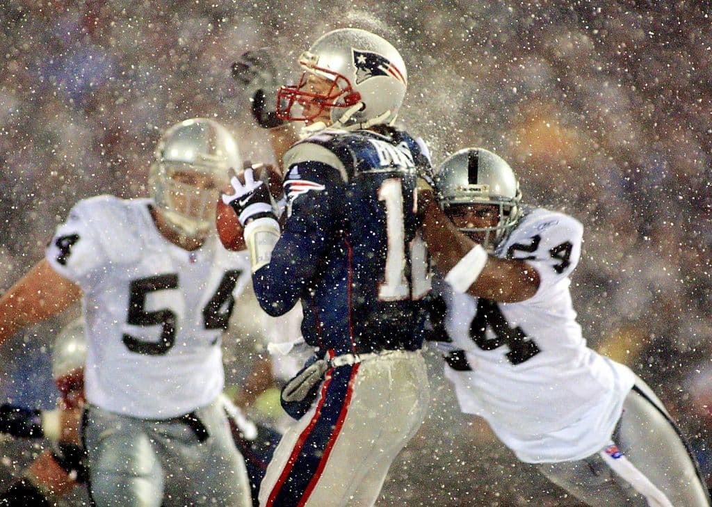 Charles Woodson llega con todo para tratar de derribar a Brady, quien encabeza la victoria de los Pats en playoffs 16-13 sobre los todavía Oakland Raiders, en 2002.