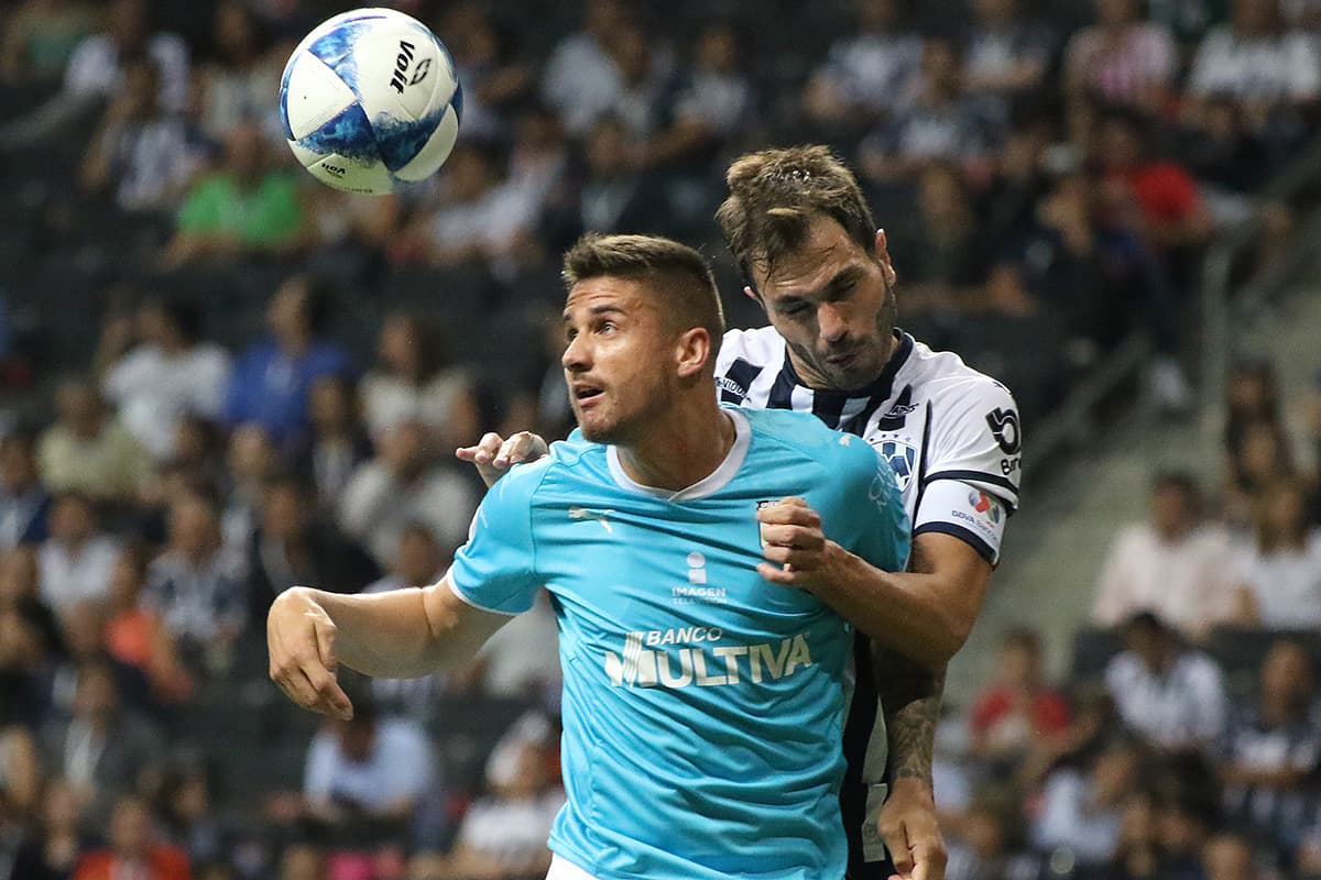 El mediocampista brasileño del Querétaro Everaldo Stum (centro) en duelo aéreo con el argentino de Monterrey José María Basanta.