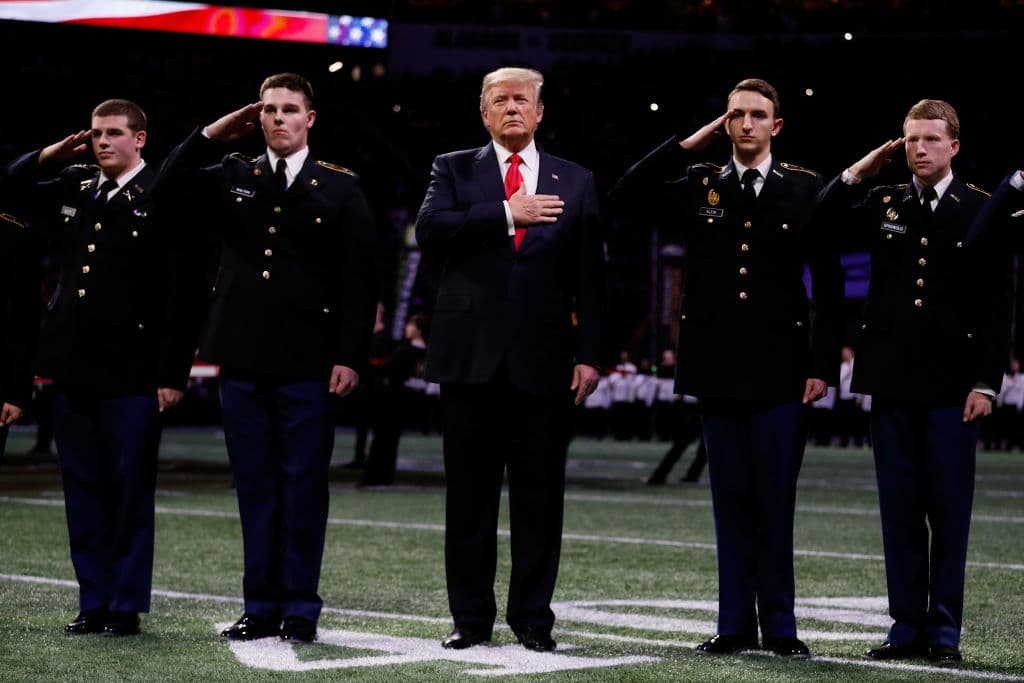 En la imagen Donald Trump durante la ceremonia del himno de EEUU previo a la final del campeonato del futbol americano universitario.