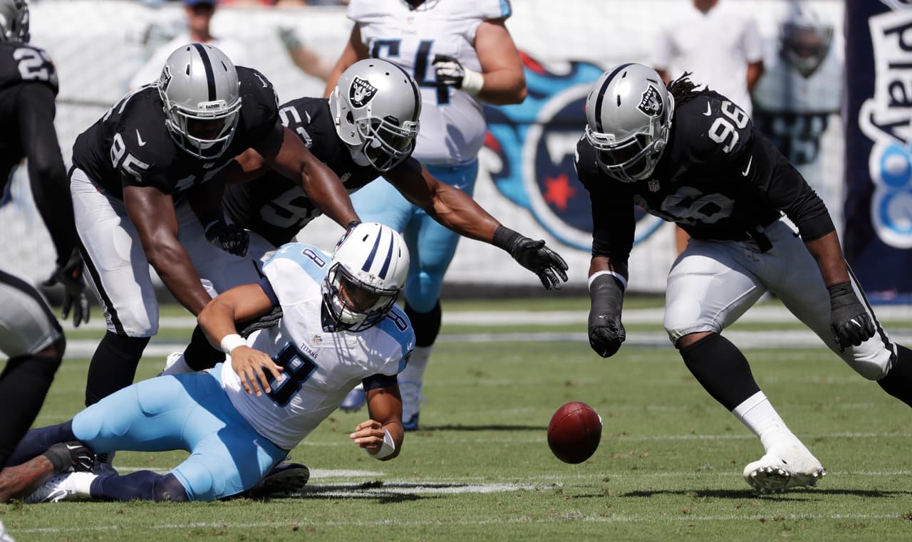 Tennessee Titans quarterback Marcus Mariota (8) fumbles the ball as Oakland Raiders defenders Jihad Ward (95) and Denico Autry (96) close in during the first half of an NFL football game Sunday, Sept. 25, 2016, in Nashville, Tenn. The Raiders recovered the ball. (AP Photo/James Kenney)