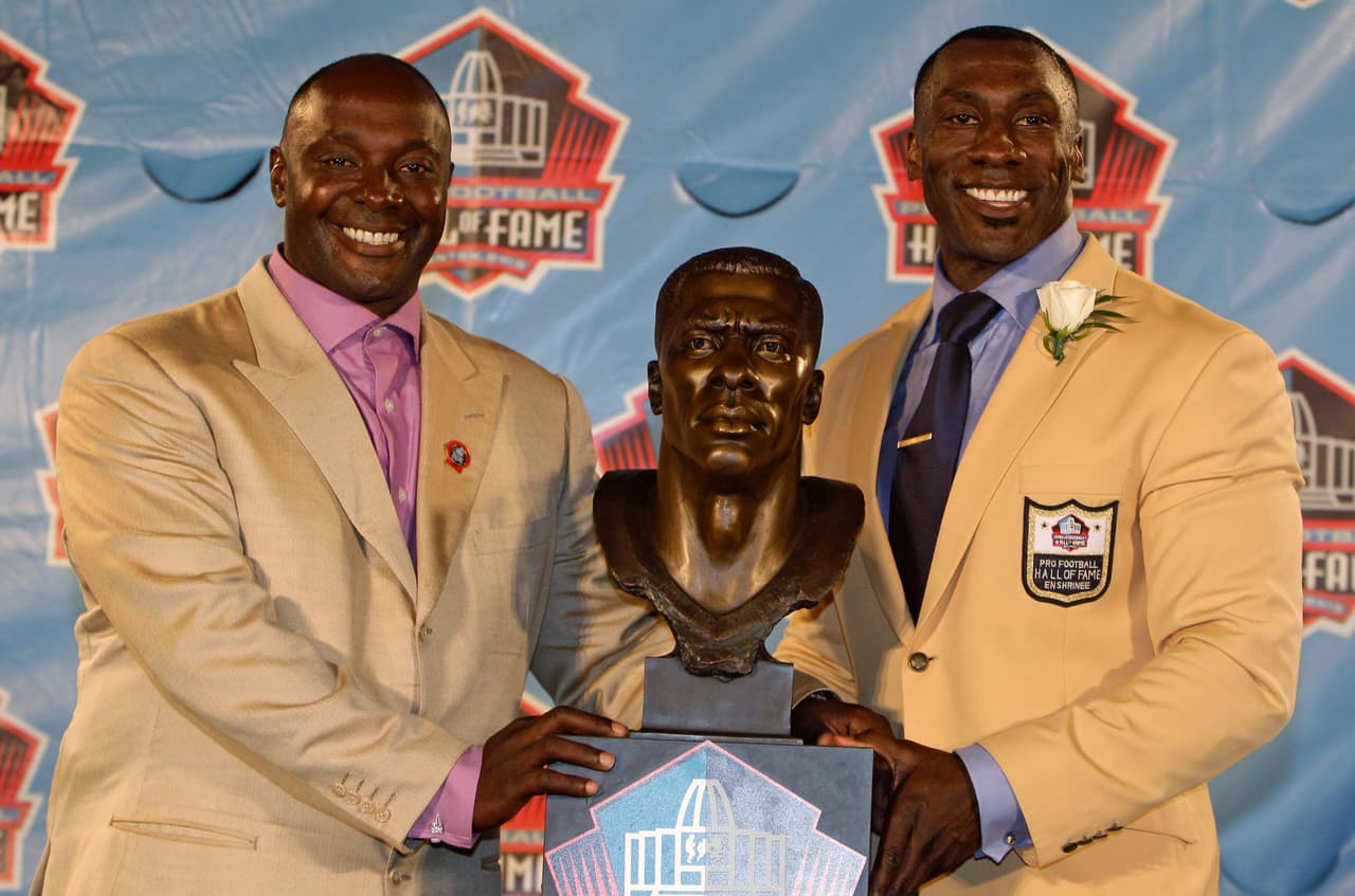 Shannon Sharpe (der) junto a su busto presentado por su hermano, Sterling, durante su inducción al Salón de la Fama NFL en 2011.