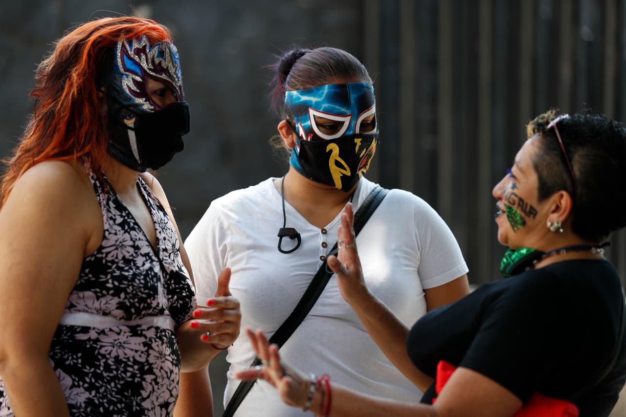 Fue a finales de marzo cuando el gobierno de la Ciudad de
<a href="https://www.univision.com/temas/mexico-city">México</a>
<b>decretó el cierre de estadios, gimnasios y centros deportivos, lo que provocó el desempleo de cientos de luchadores.</b>
<br>
<br>Las gladiadoras Migala, Skarlet y La Zorra, conversan mientras esperan en la fila para recibir su despensa.