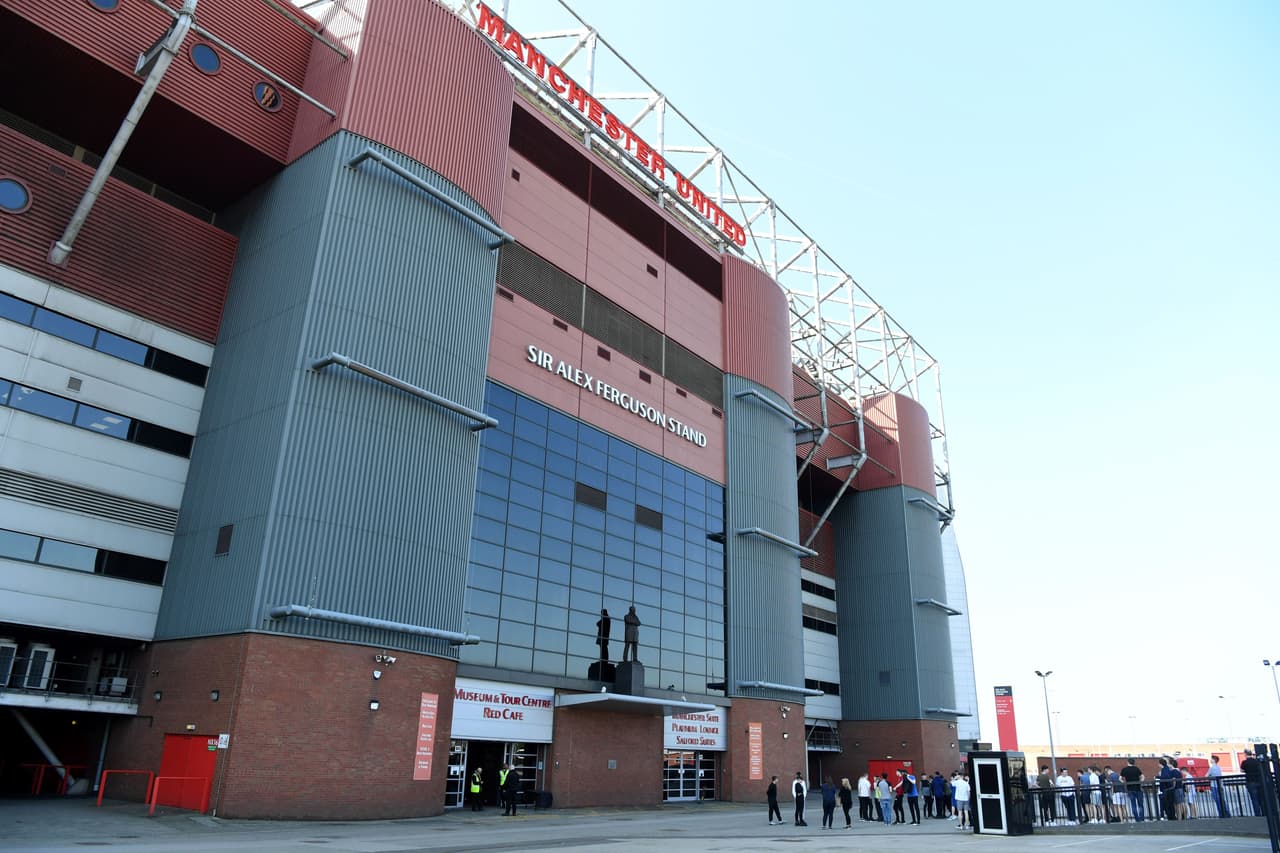 Visitors walk past the Sir Alex Ferguson Stand featuring a statue of legendary football manager Sir Alex Ferguson at Old Trafford football stadium in Manchester on May 6, 2018. - Messages of support continued to pour in as legendary football manager Sir Alex Ferguson fought for his life on May 6, 2018, following emergency surgery for a brain haemorrhage. (Photo by Paul ELLIS / AFP) (Photo credit should read PAUL ELLIS/AFP/Getty Images)