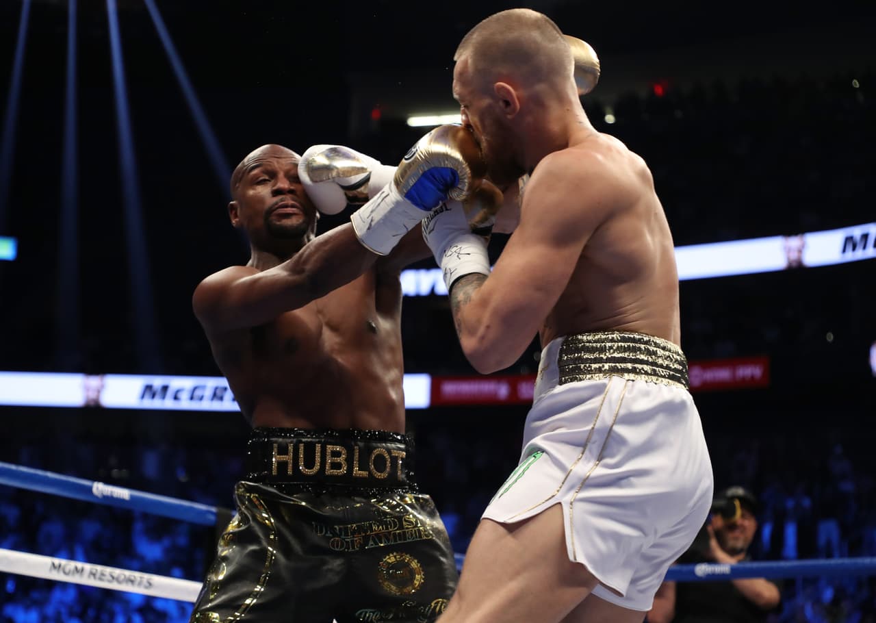 LAS VEGAS, NV - AUGUST 26: (R-L) Conor McGregor throws a punch at Floyd Mayweather Jr. during their super welterweight boxing match on August 26, 2017 at T-Mobile Arena in Las Vegas, Nevada. (Photo by Christian Petersen/Getty Images)