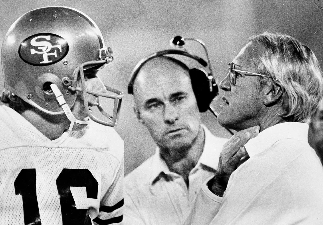 San Francisco 49ers head coach Bill Walsh, right, talks with quarterback Joe Montana on the sidelines during Super Bowl XVI game with the Cincinnati Bengals in Pontiac, Mich., Jan. 25, 1982. Walsh, a former assistant with the Bengals who is credited with shaping the style of Bengals quarterback Ken Anderson, molded an offensive attack around Montana to take the Super Bowl title. (AP Photo)