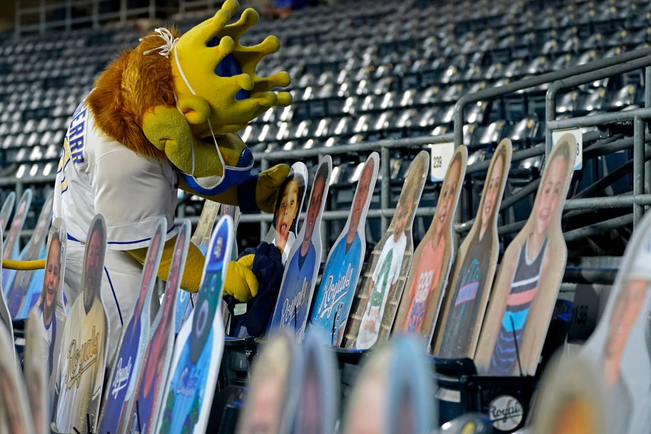 La mascota de Kansas City Royals, Sluggerrr, limpia el agua que le cayó a un fan de cartón.