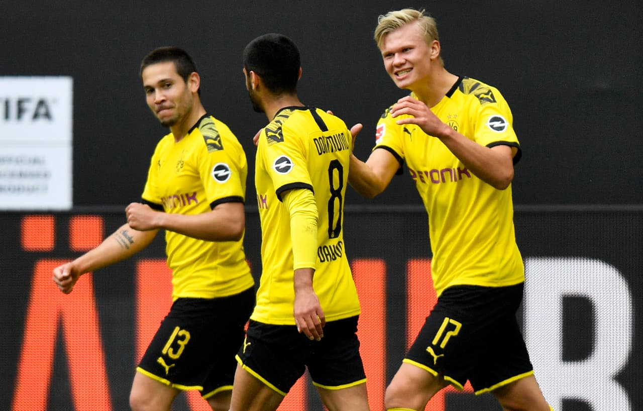 Dortmund's Portuguese defender Raphael Guerreiro (L) celebrates with Dortmund's German midfielder Mahmoud Dahoud (C) and Dortmund's Norwegian forward Erling Braut Haaland after scoring his side's second goal during the German first division Bundesliga football match BVB Borussia Dortmund v Schalke 04 on May 16, 2020 in Dortmund, western Germany as the season resumed following a two-month absence due to the novel coronavirus COVID-19 pandemic. (Photo by Martin Meissner / POOL / AFP) / DFL REGULATIONS PROHIBIT ANY USE OF PHOTOGRAPHS AS IMAGE SEQUENCES AND/OR QUASI-VIDEO (Photo by MARTIN MEISSNER/POOL/AFP via Getty Images)