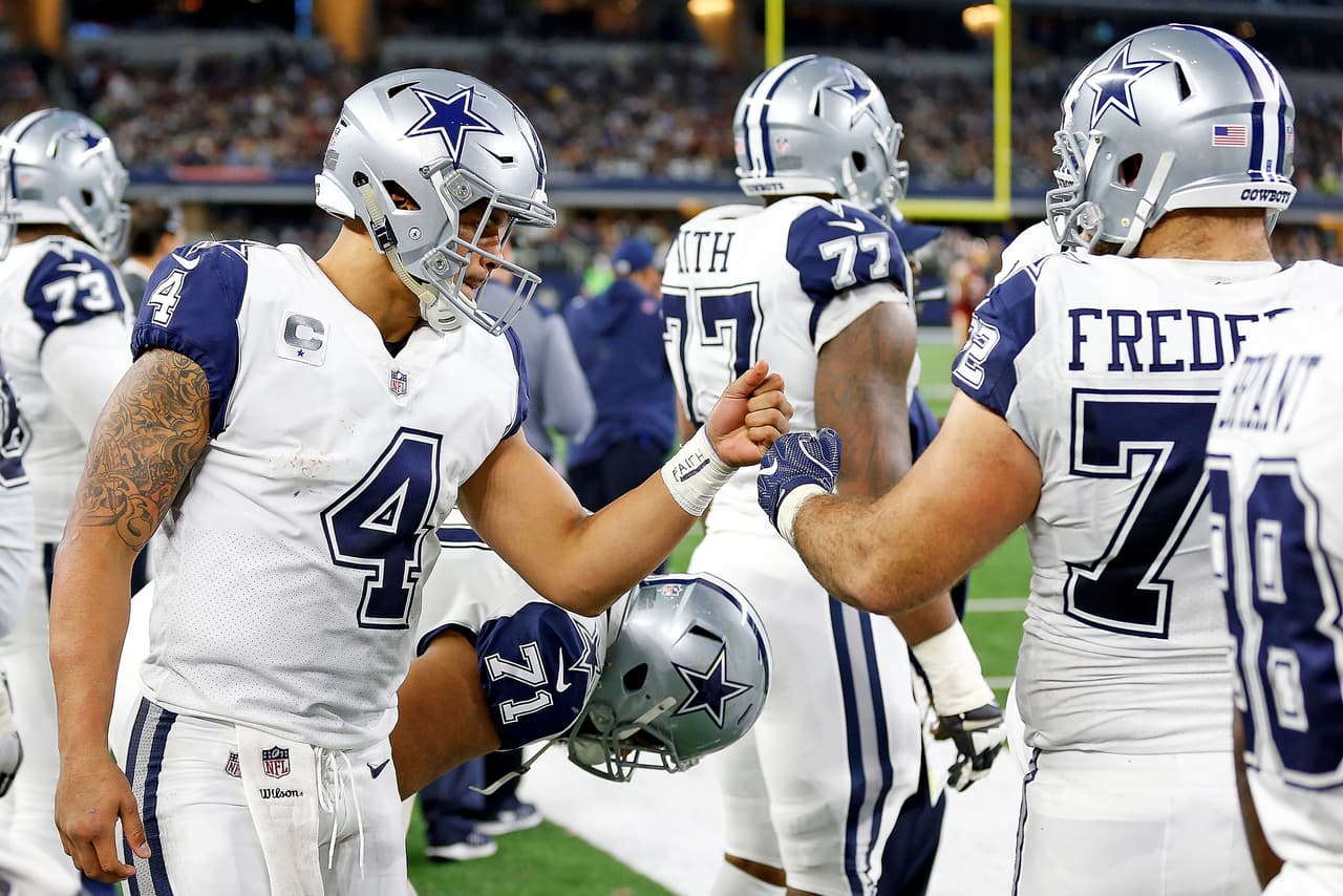 Dallas Cowboys quarterback Dak Prescott (4) bumps fists with center Travis Frederick (72) on the sideline during a 2017 NFL week 13 regular season game against the Washington Redskins, Thursday, Nov. 30, 2017 in Arlington, Texas. The Cowboys defeated the Redskins, 38-14. (James D. Smith via AP)