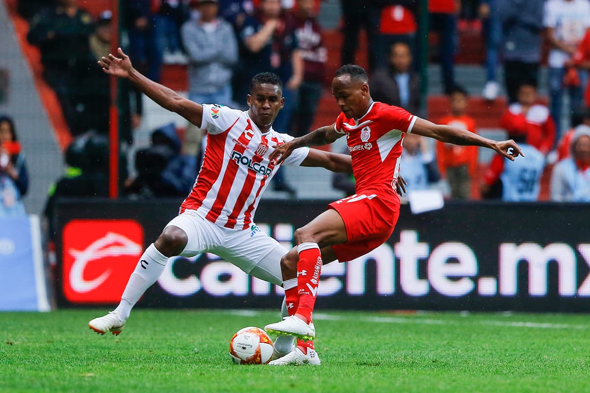 El hondureño del Necaxa Brayan Beckeles (izquierda) trata de detener el ataque del colombiano Luis Quiñones del Toluca (derecha).