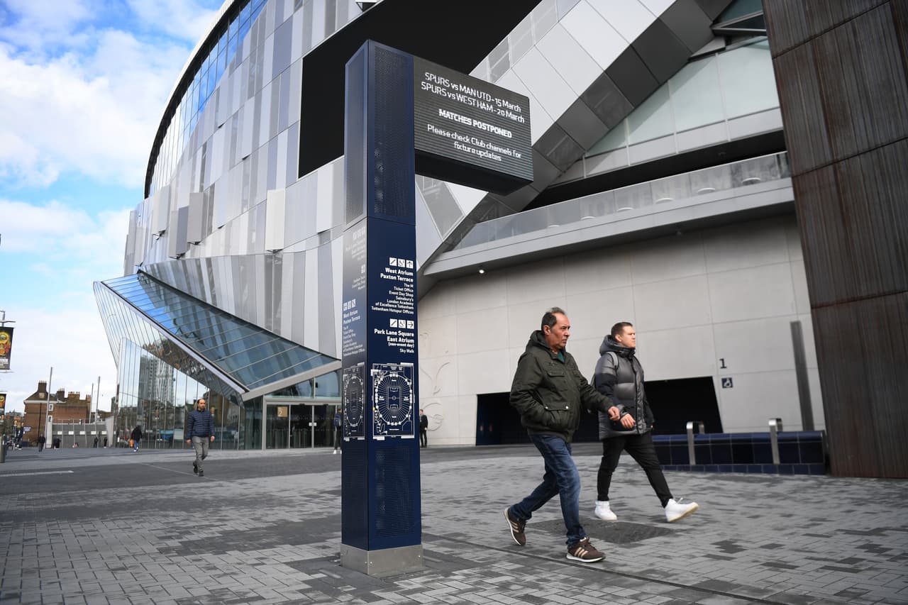 Una vista al exterior del Tottenham Hotspur Stadium permite ver que algunas personas pasan por ahí camino a sus labores.