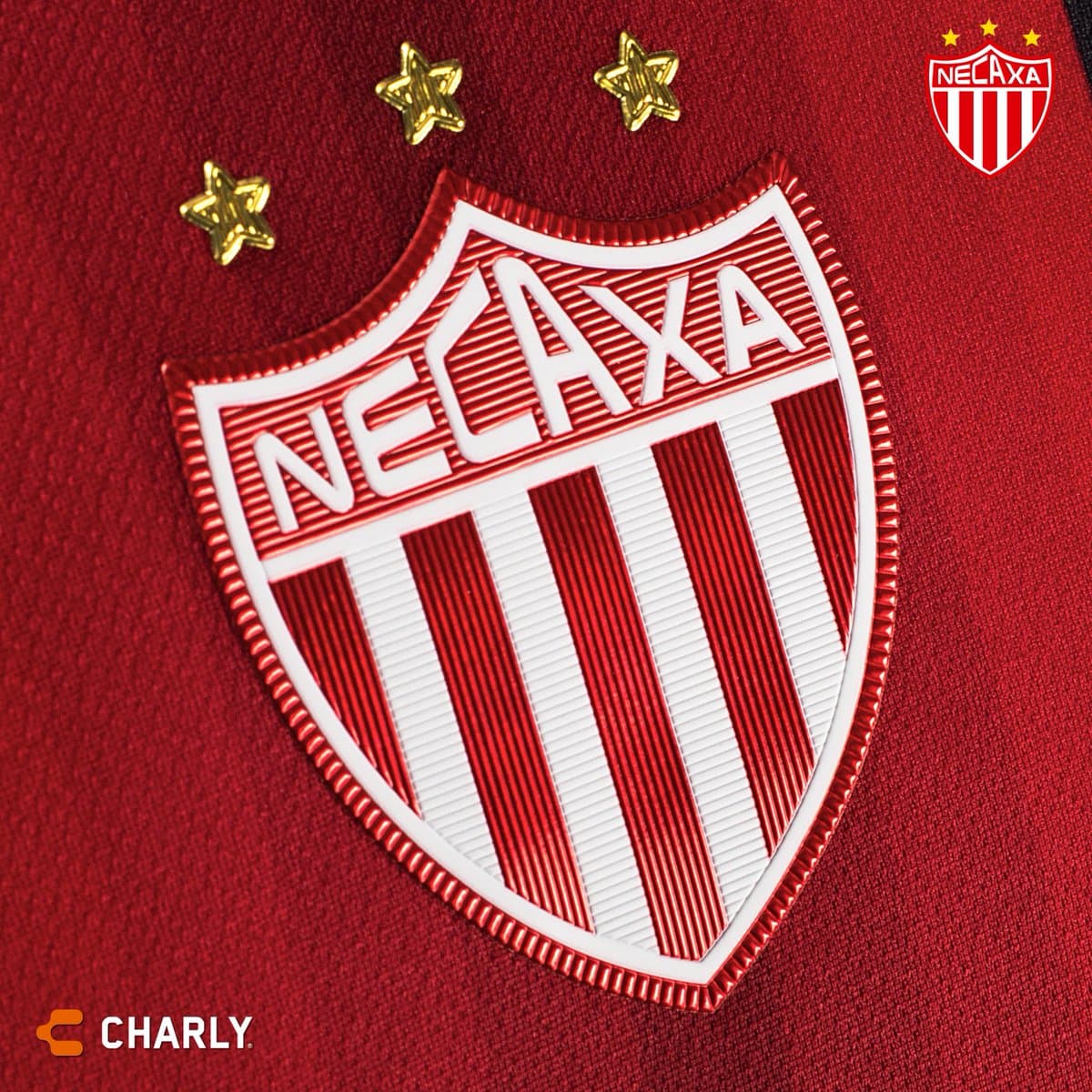 El escudo del club aparece con acabados metálicos y está enmarcado por las tres estrellas doradas que refleja los títulos del Rayo.