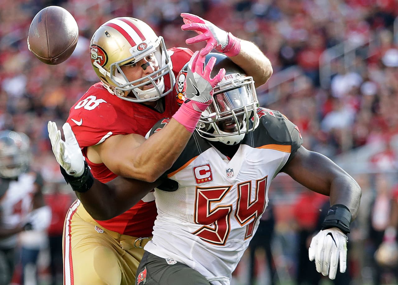 Vance McDonald de los 49ers y el defensivo de los Buccaneers, Lavonte David, peleando por el ovoide.