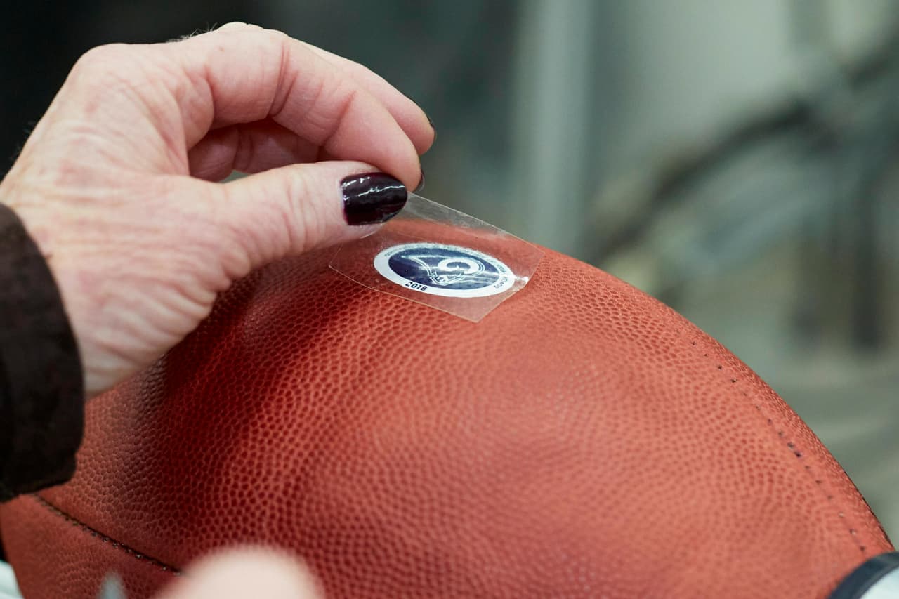 Y aquí están colocando el de los Rams sobre el cuero del ovoide.