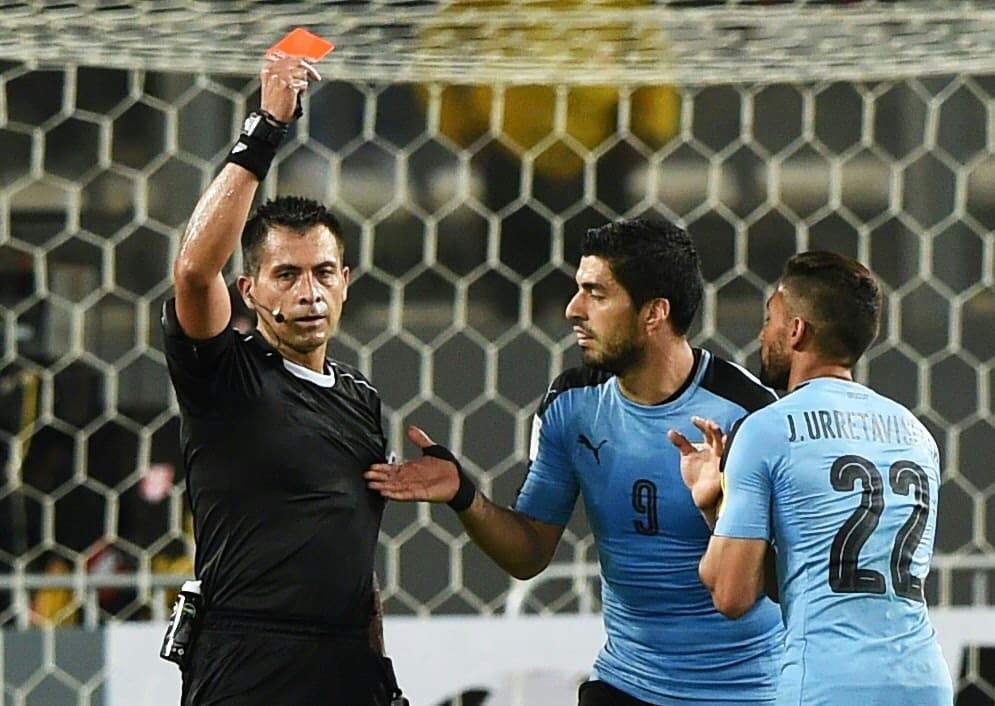 Chilean referee Julio Bascunan shows the red card to Uruguay's Jonathan Urretaviscaya (R) during the 2018 FIFA World Cup qualifier football match Peru vs Uruguay, in Lima on March 28, 2017. / AFP PHOTO / CRIS BOURONCLE (Photo credit should read CRIS BOURONCLE/AFP/Getty Images)